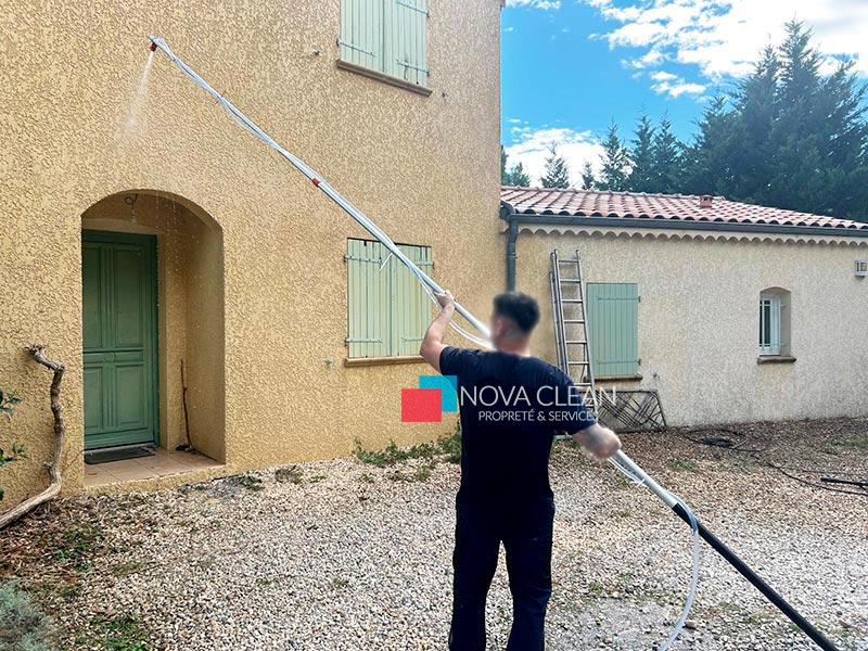 photo du technicien en plein nettoyage au karcher de la façade encrassé de maison